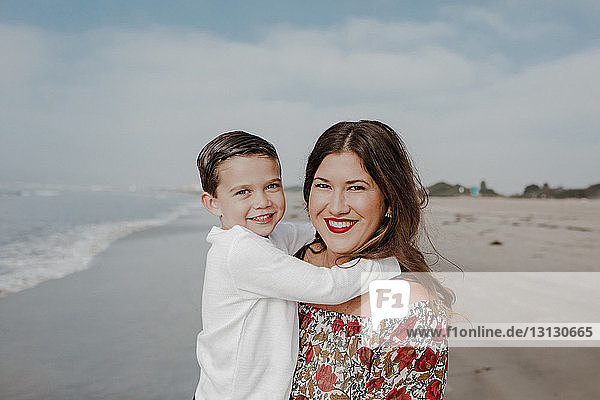 Porträt von fröhlicher Mutter und Sohn am Strand