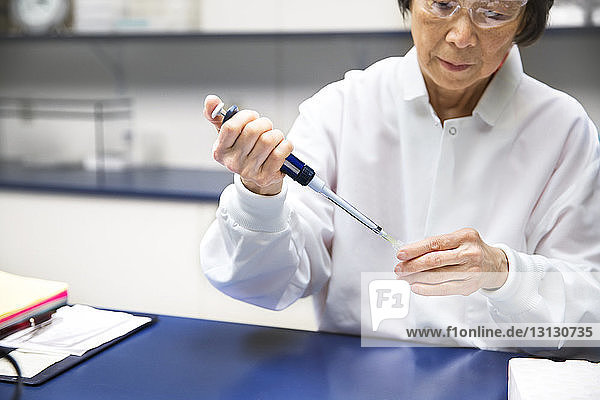 Leitende Wissenschaftlerin benutzt Pipette während des Experiments im Labor