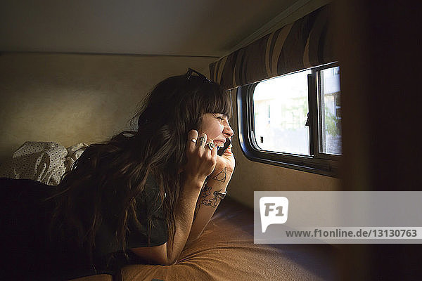 Glückliche Frau  die während einer Reise im Wohnmobil mit einem Smartphone telefoniert