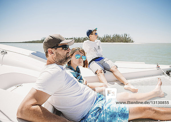 Family relaxing in boat on sea against clear sky during sunny day