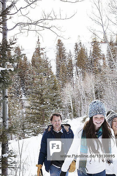 Family walking in snowy forest against sky