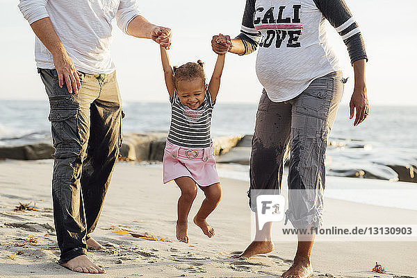 Niedriger Anteil von Eltern  die mit ihrer Tochter bei Sonnenuntergang am Strand spielen