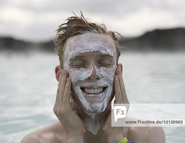 Fröhlicher Tourist trägt Schlamm in der Blauen Lagune auf