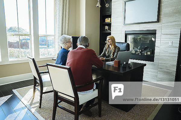 Senior couple discussing with financial advisor while sitting in office