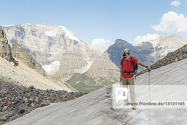 Full length of man standing on snowcapped mountain at Banff national park against sky