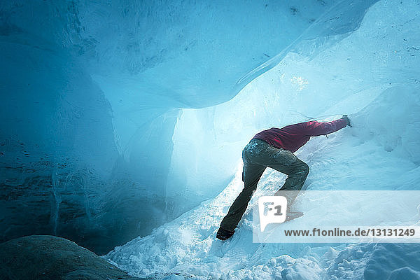 Low angle view of hiker ice climbing in cave