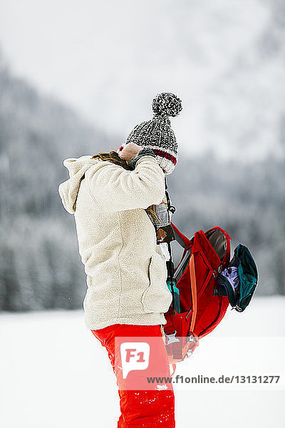 Seitenansicht einer Frau mit Rucksack auf schneebedecktem Feld stehend