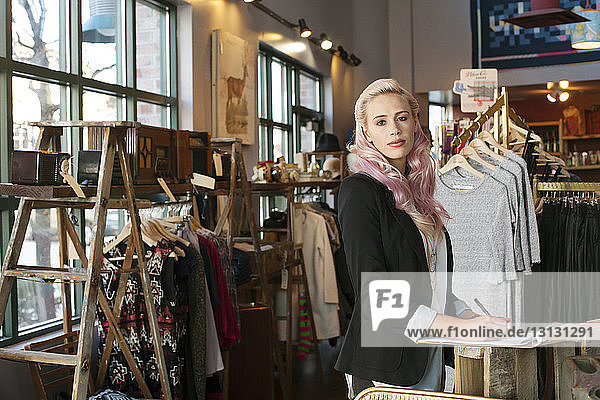 Portrait of female owner writing on clipboard in clothing store