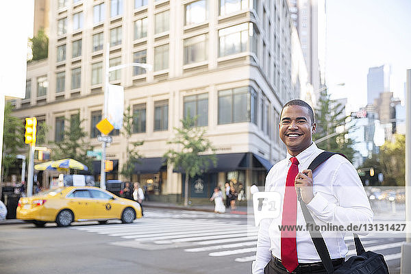Portrait of confident businessman with bag standing on city street
