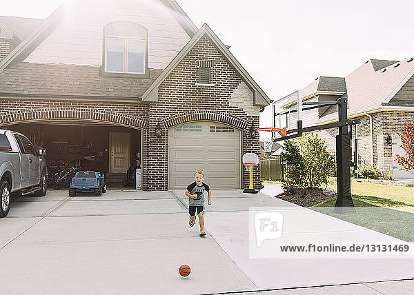 Junge läuft hinter Basketball auf Einfahrt