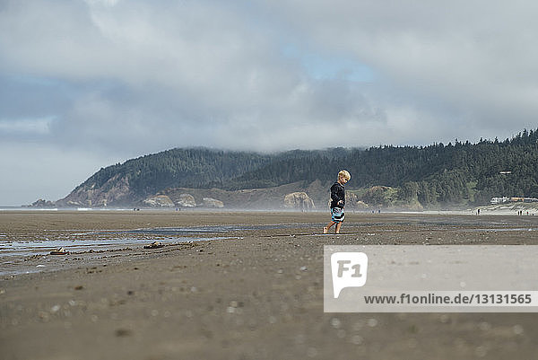 Seitenansicht eines Jungen  der am Strand am Ufer spazieren geht