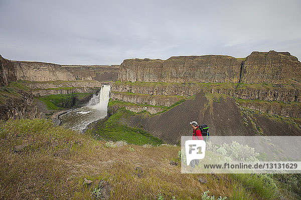 Full length of man standing against waterfall at Palouse Falls State Park