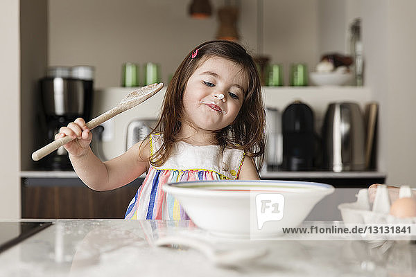 Süßes Mädchen bereitet zu Hause in Kücheninsel Essen zu