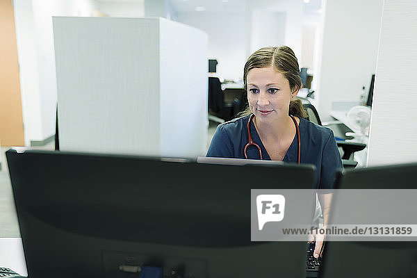 Zuversichtliche Ärztin benutzt Desktop-Computer im Krankenhaus