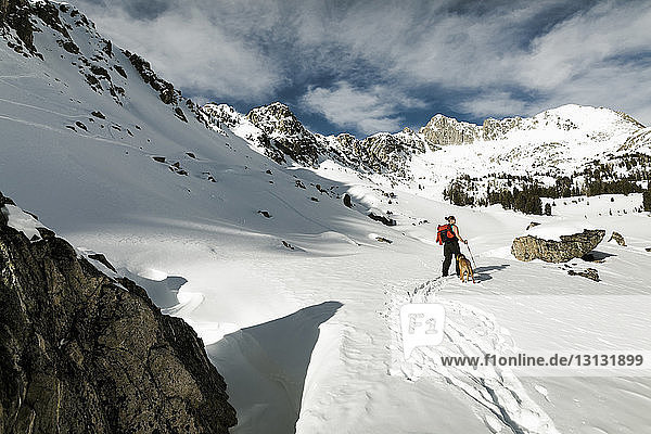Wanderin mit Hund gegen schneebedeckte Berge