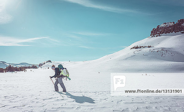 Seitenansicht einer Wanderin beim Wandern in verschneiter Landschaft