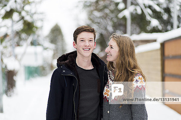 Portrait of happy teenage boy with sister standing on footpath