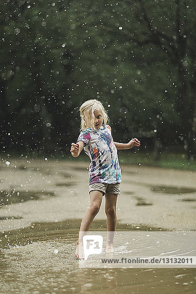 Full length of girl playing in puddle at park