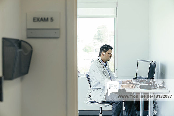 Seitenansicht eines Arztes bei der Arbeit im Krankenhaus am Desktop-Computer
