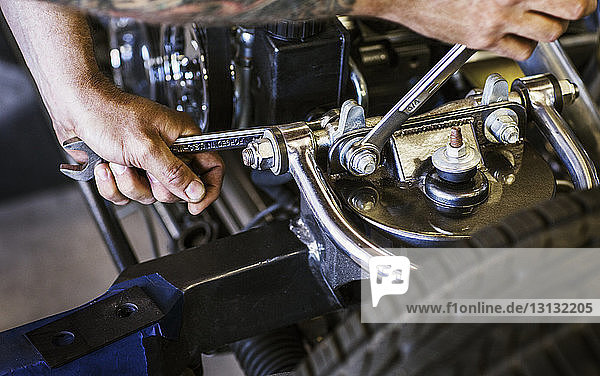Beschnittenes Bild von Händen  die Muttern eines Automotors in einer Autowerkstatt befestigen