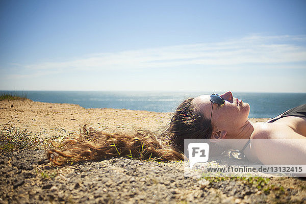 Kopfschuss einer auf Sand liegenden Frau gegen den Himmel