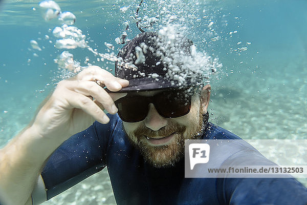 Portrait of happy man wearing sunglasses while swimming undersea