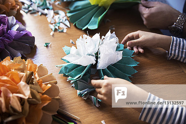 Beschnittenes Bild eines Mädchens und eines Vaters  die bei Tisch Papierblumen basteln