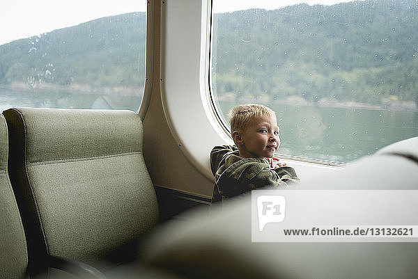 Porträt eines Jungen  der am Fenster sitzt  während er im Zug reist