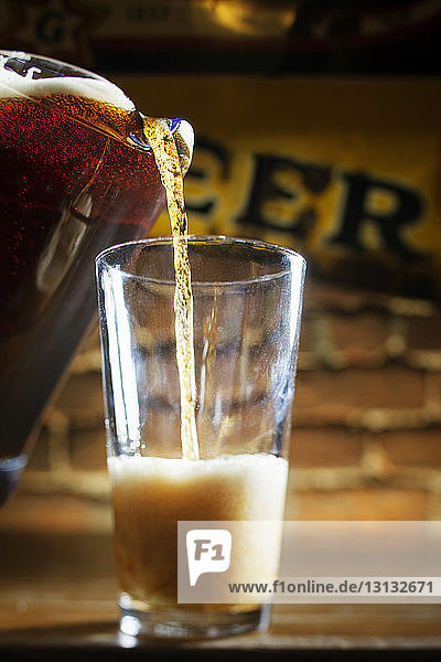 Bier wird aus einem Krug in Glas gegossen