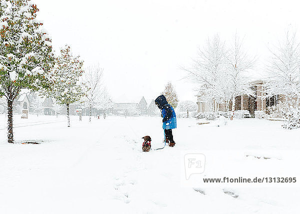 Boy with Shih Tzu standing on snow covered field