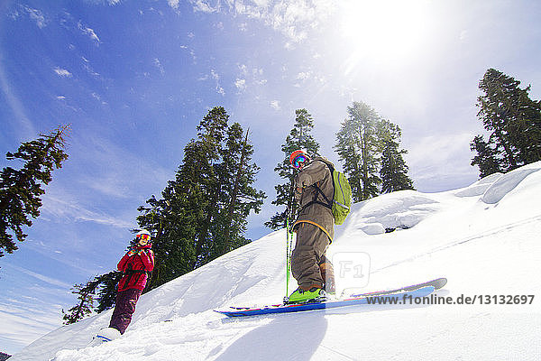 Tiefwinkelansicht eines Mannes und einer Frau  die auf einem schneebedeckten Berg gegen den Himmel stehen