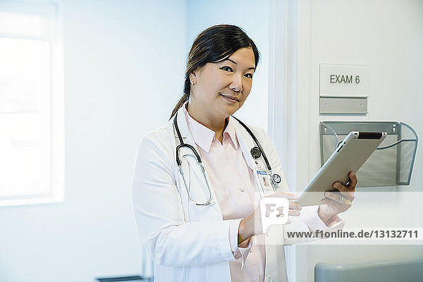 Portrait of female doctor holding tablet computer in hospital corridor