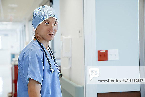 Portrait of confident surgeon standing in hospital corridor