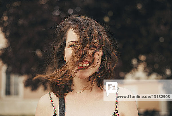 Porträt einer glücklichen jungen Frau mit zerzaustem Haar im Freien