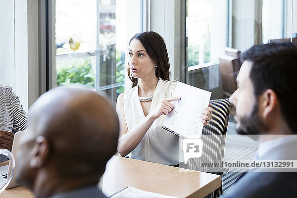 Businesswomen showing pie chart to colleagues in meeting