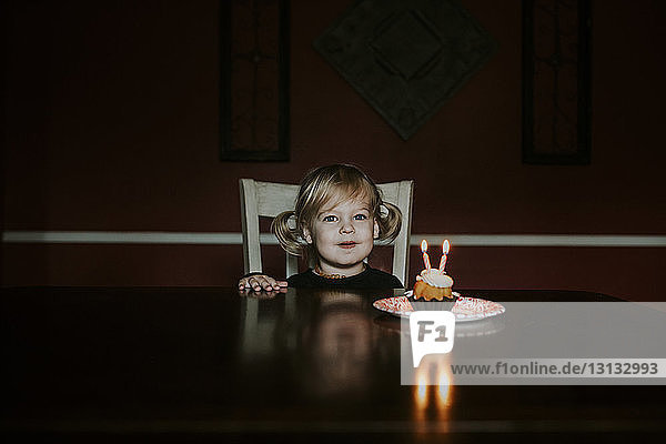 Porträt eines süßen Mädchens mit Geburtstagskuchen auf dem heimischen Tisch
