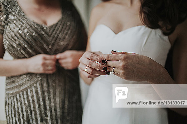 Midsection of bride wearing wedding dress while standing by bridesmaid