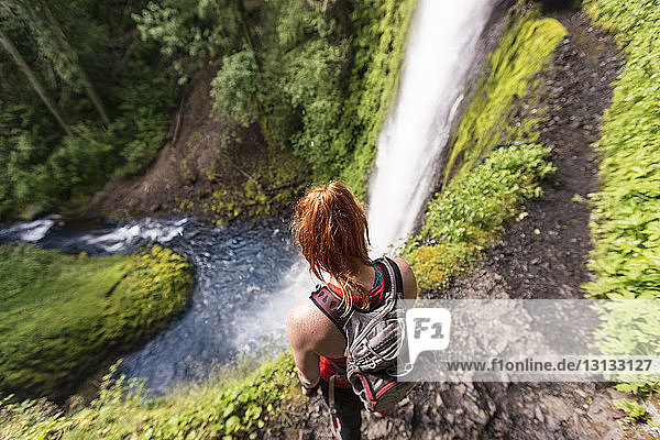 High angle view of female hiker with backpack standing on Eagle Creek Trail against Tunnel Falls