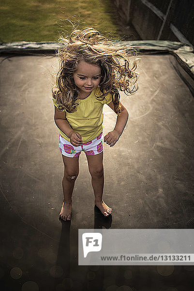 High angle view of playful girl standing on trampoline