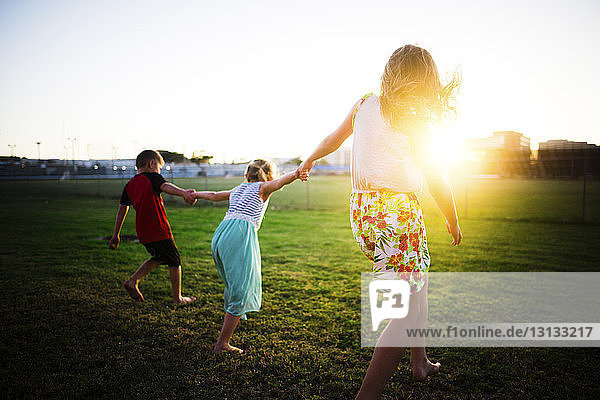 Mutter und Kinder spielen im Park während des Sonnenuntergangs