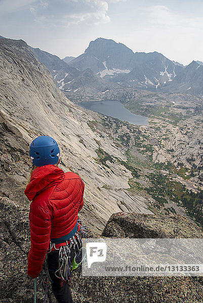 Hochwinkelaufnahme einer Wanderin mit Bergsteigerausrüstung  die auf einer Klippe gegen den Himmel steht