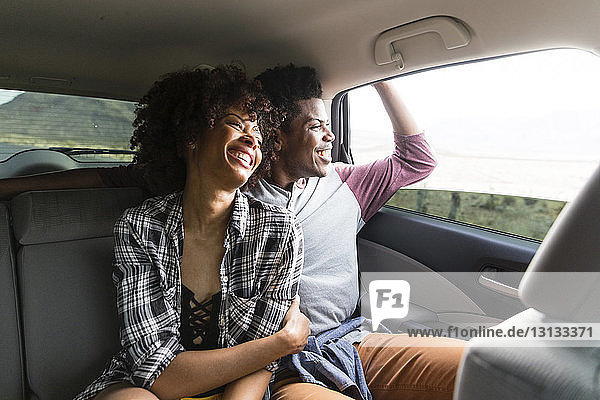 Glückliches Paar schaut durchs Fenster  während es im Auto unterwegs ist