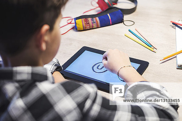 Nahaufnahme einer Zeichnung eines Jungen auf einem Tablet-Computer bei Tisch