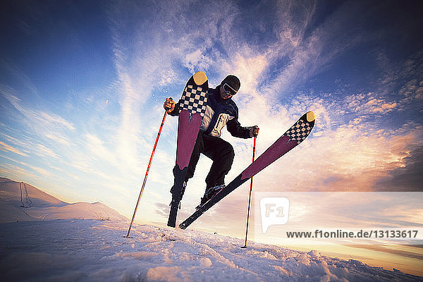 Low angle view of skier jumping on snow against sky