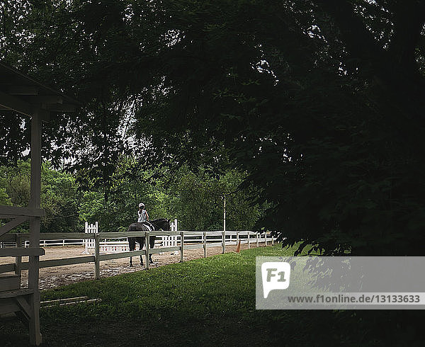 Rückansicht eines Mädchens beim Reiten auf einer Ranch