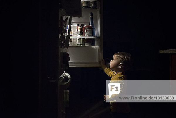 Porträt eines Jungen ohne Hemd  der mit Wasser spielt  während er in der Küchenspüle sitzt