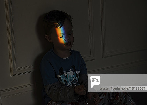 Spektrum fällt auf das Gesicht des Jungen  während er in der Dunkelkammer sitzt