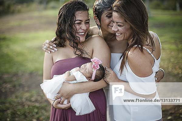 Happy family with newborn baby girl standing at park