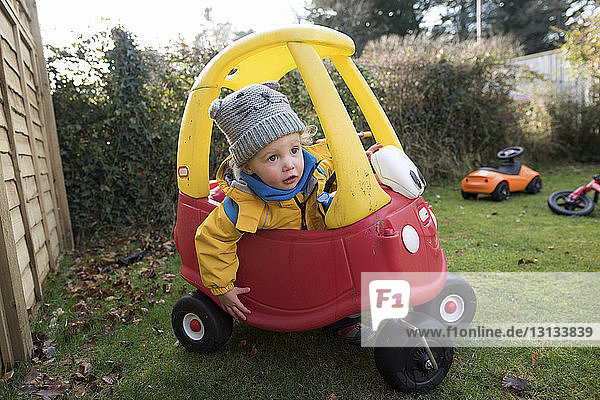 Girl driving toy car in backyard