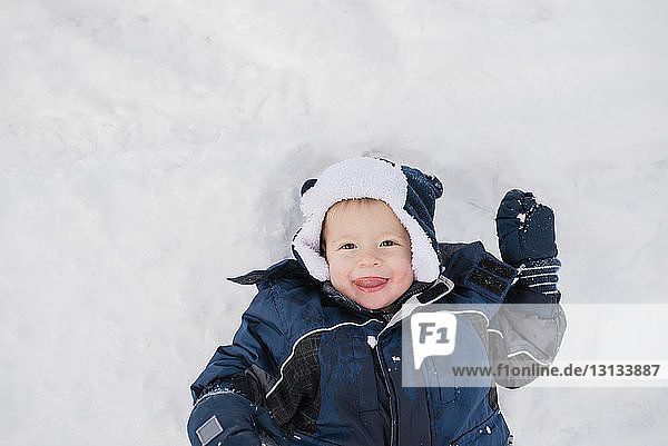 Overhead portrait of cute baby boy lying on snow